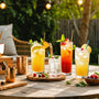 Colorful summer cocktails and bamboo bar tools on a sunny patio, perfect for High-Impact Recipe Guides fans