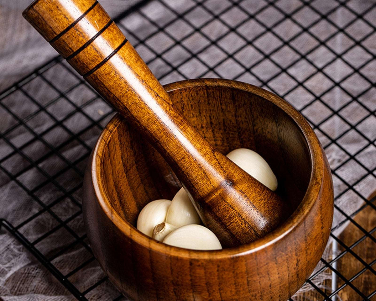 Bamboo wooden mortar and pestle set with garlic cloves, perfect for grinding spices and herbs.