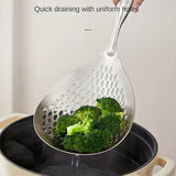 Metallic slotted spoon with broccoli being used to drain water from a pot.