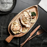 Wooden plate with oysters on a dark surface, featuring the brand 'Komorela'.