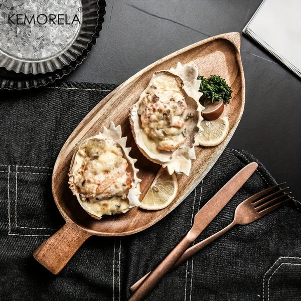 Wooden plate with oysters on a dark surface, featuring the brand 'Komorela'.