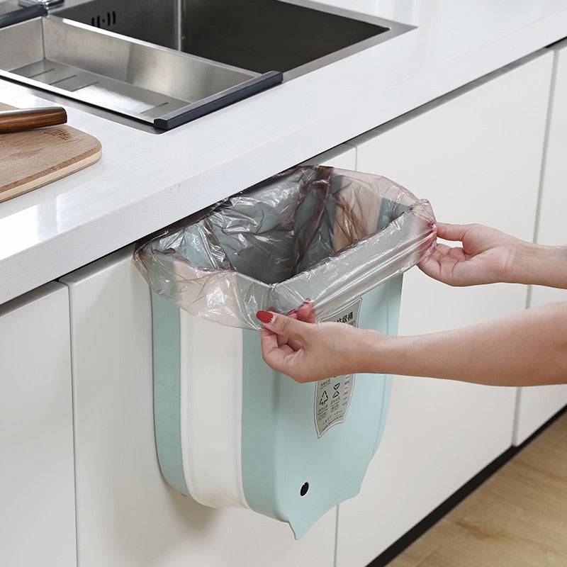 Wall mounted foldable waste bin on kitchen cabinet door being used