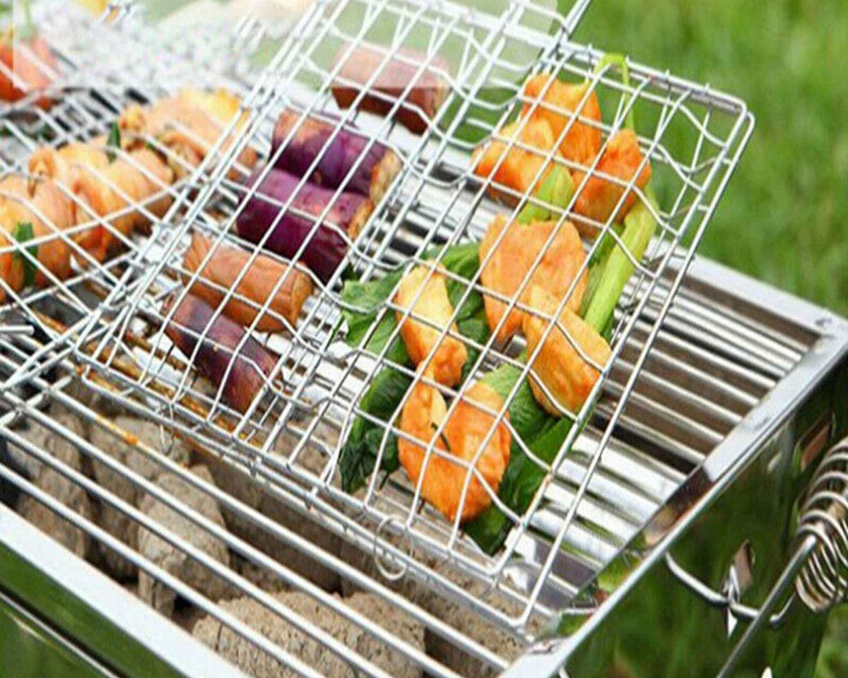 Barbecue grilling basket with long handle grilling vegetables and meat on outdoor grill.