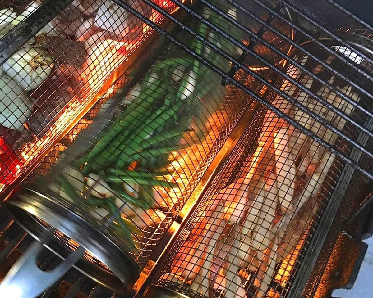Stainless steel BBQ grilling basket with vegetables over flames.