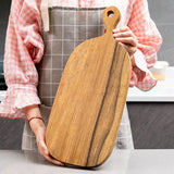 Person holding a premium wooden chopping board in a kitchen setting.