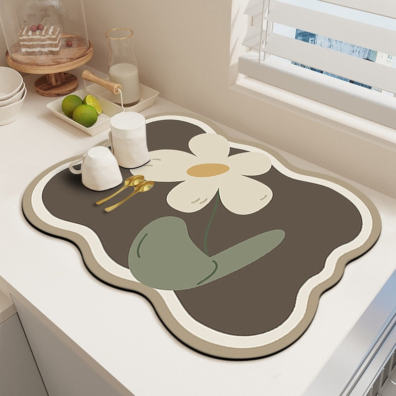 Absorbent kitchen dish drying mat with floral design on countertop.