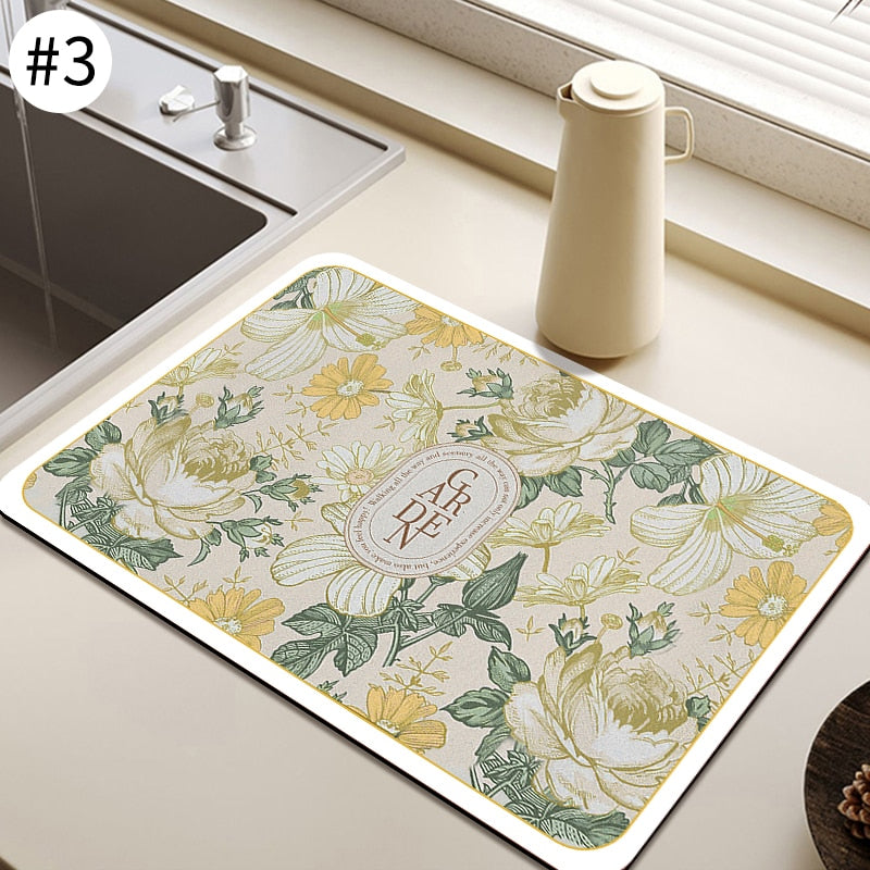 Absorbent kitchen dish drying mat with floral pattern placed near a sink.