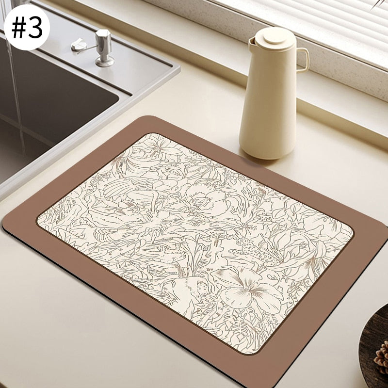 Absorbent kitchen dish drying mat with floral design on countertop near sink.
