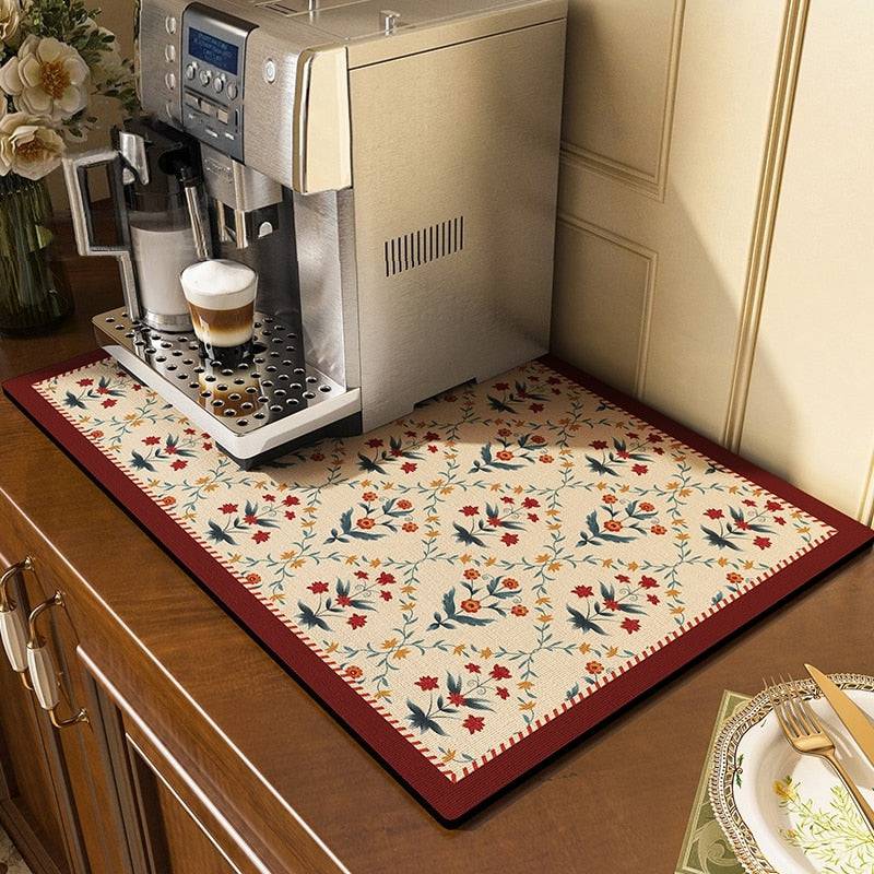 Absorbent kitchen dish drying mat with floral design under a coffee machine.