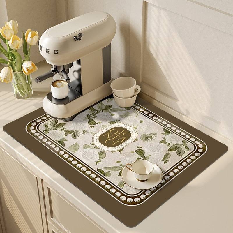 Absorbent kitchen dish drying mat with floral pattern under espresso machine.