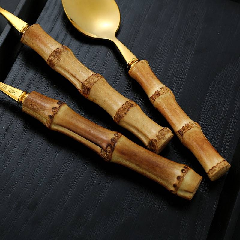Stainless steel tableware set with natural bamboo handles, includes cutlery and steak knives.