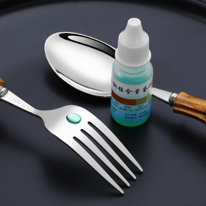Stainless steel tableware set with bamboo handles, featuring fork and spoon on black background.