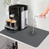 Kitchen countertop with a super absorbent drainer mat under a coffee machine, water being poured nearby.