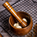 Bamboo wooden mortar and pestle set with garlic cloves, ideal for grinding spices and herbs.