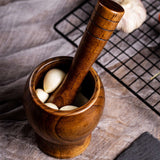 Bamboo wooden mortar and pestle set with garlic bulbs, ideal for grinding spices and herbs.