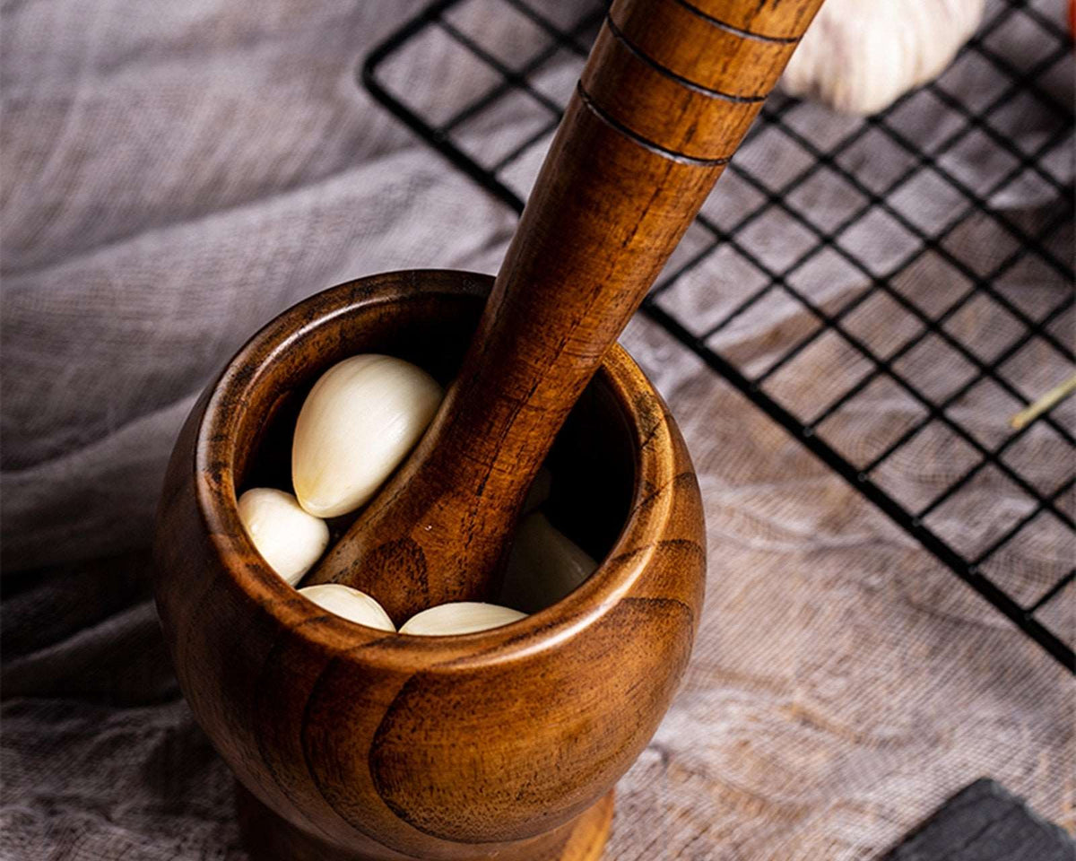 Bamboo wooden mortar and pestle set with garlic bulbs, ideal for grinding spices and herbs.