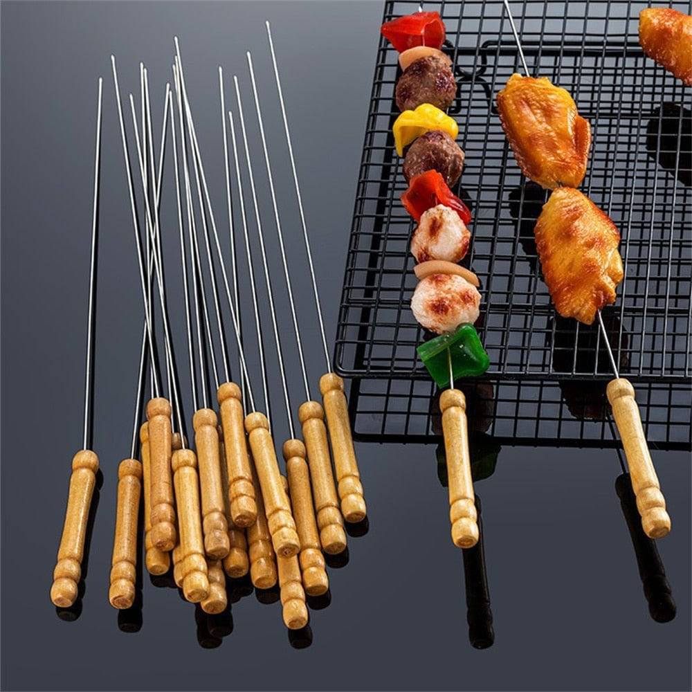 Stainless steel skewers with wooden handles and grilled food on the barbecue.