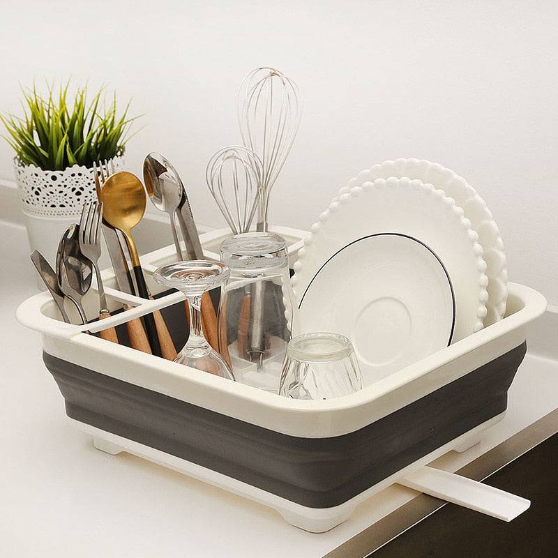 Foldable dish rack with dishes and utensils, kitchen drainer tool.