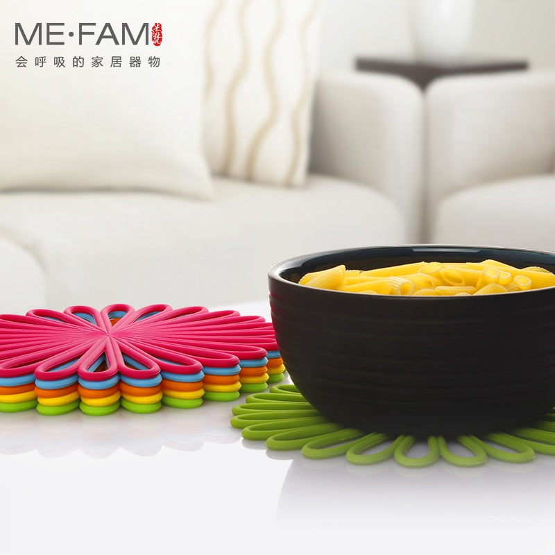 Silicone trivet mat with geometric flower design, shown in colorful woven pads beneath a black bowl, ideal for heat resistance and table protection.