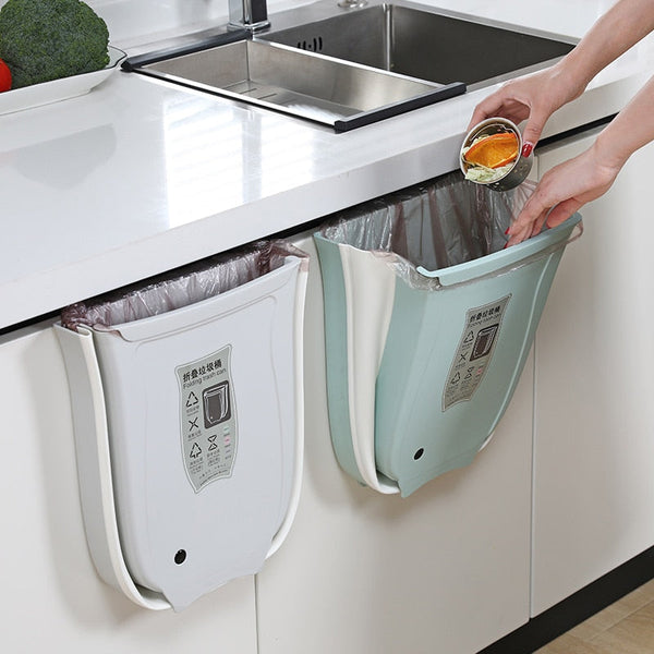 Wall mounted foldable waste bin hanging on kitchen cabinet, showcasing practicality and space-saving design for efficient waste management.
