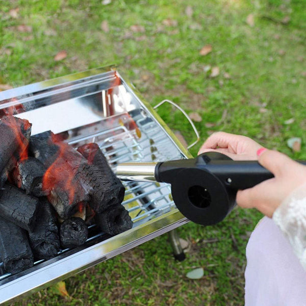 Hand-held outdoor BBQ fan air blower used to ignite charcoal on a grill.