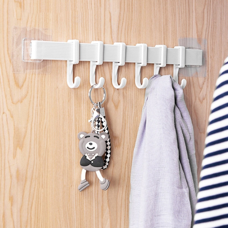 Multifunction Storage Hook with 6 hooks on wooden surface holding keychain and towel.