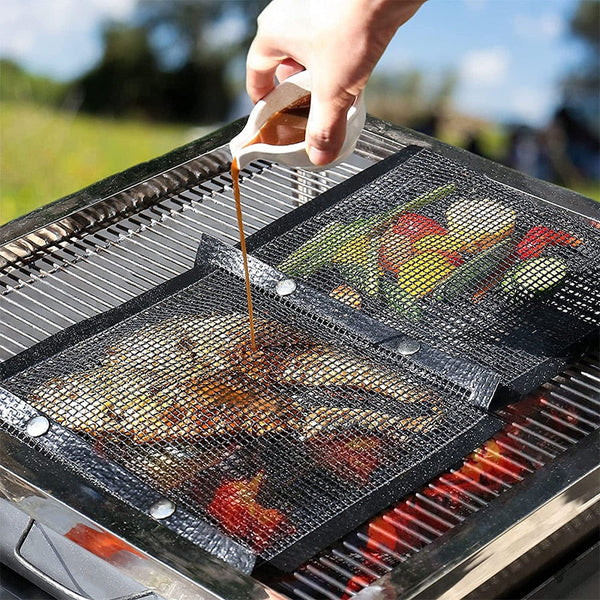 Reusable non-stick mesh grill bags on BBQ with vegetables and meat cooking.