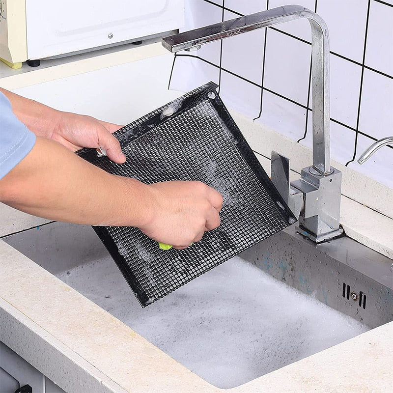 Reusable non-stick mesh grill bag being cleaned at the sink, perfect for BBQ use.