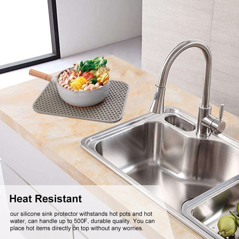 Silicone sink protector mat on kitchen counter next to stainless steel sink, heat resistant up to 500F.